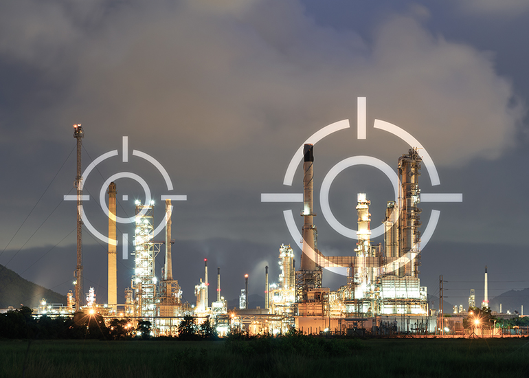 Beleuchtete Industrieanlage bei Nacht mit mehreren hohen Schornsteinen und technischen Anlagen. Über dem Motiv liegen große, halbtransparente Zielkreise als grafisches Element.
