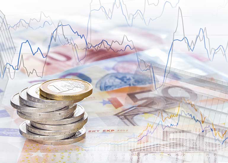 Gestapelte Euro-Münzen auf Euro-Banknoten vor einem Hintergrund mit dargestellten Finanz- und Kursdiagrammen.
